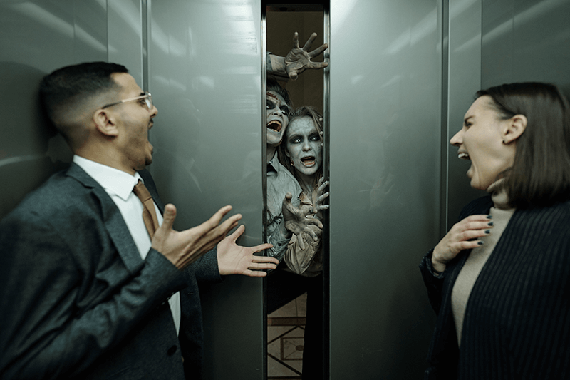 Two corporate professionals trying to navigate career change trapped on an elevator with zombies trying to attack on Halloween